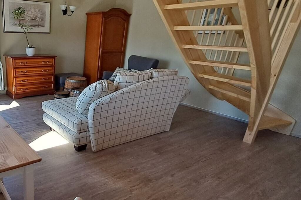 Ein Zimmer mit einer Couch, einem Holzschrank und einer Holztreppe.