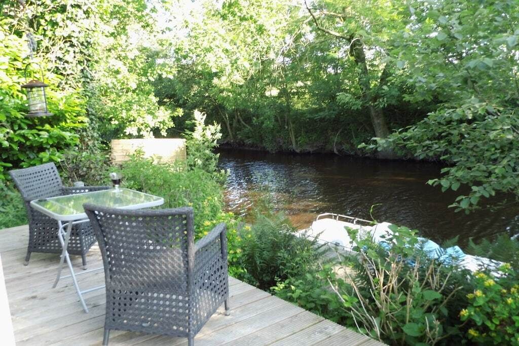 A wooden deck with outdoor furniture overlooking a river.