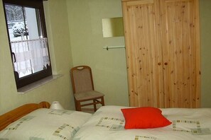 Ein Schlafzimmer mit einem Bett, einem Sessel, einem Holzschrank und einem Fenster mit Blick auf eine verschneite Landschaft.