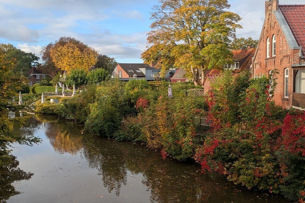 Ein Fluss mit Häusern an einem Ufer und einem Backsteingebäude am anderen.