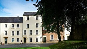 A building with multiple windows and doors, a paved area in front, and a tree to the right.