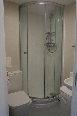 A glass-enclosed shower stall with a toilet and sink in a corner bathroom. - St Chads College  (Durham)