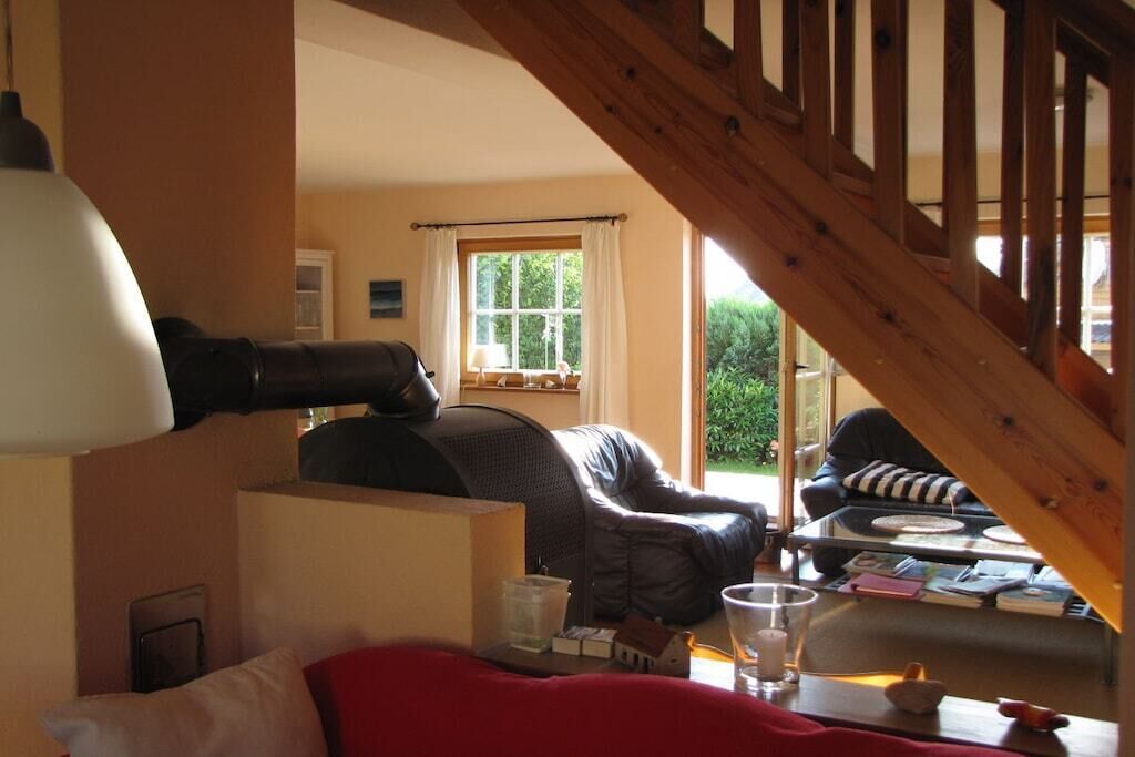 A cozy living room with a fireplace, a comfortable sofa, a coffee table, and a staircase leading to an upper level.