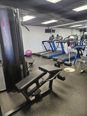 Ein Fitnessstudio mit Laufbändern, einem Ergometer und einer Gewichtbank.