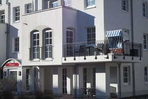 A multi-story building with a reception area, balconies, and a small outdoor seating area. - House Sea View Apartment A 1.04 (Baabe)