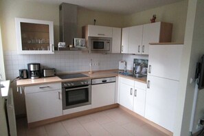 A kitchen with white cabinets, a microwave, an oven, a coffee maker, and a dishwasher. - House Sea View Apartment A 1.04 (Baabe)