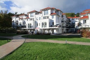 A multi-story building with a central entrance, surrounded by a well-maintained lawn and a paved walkway. - House Sea View Apartment A 1.04 (Baabe)