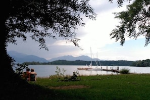 Ein See mit einer Anlegestelle und einem Segelboot, umgeben von Bergen und Bäumen.