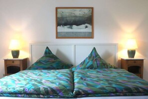 A bed with a patterned bedspread, two nightstands with lamps, and a framed picture on the wall. - Holiday apartment with 1 bedroom (Samerberg)