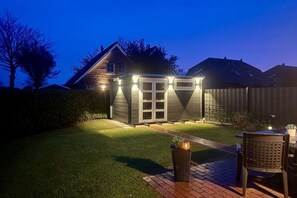 A backyard with a patio area, a small shed, and a well-maintained lawn. - Holiday home with 2 bedrooms (Greetsiel)