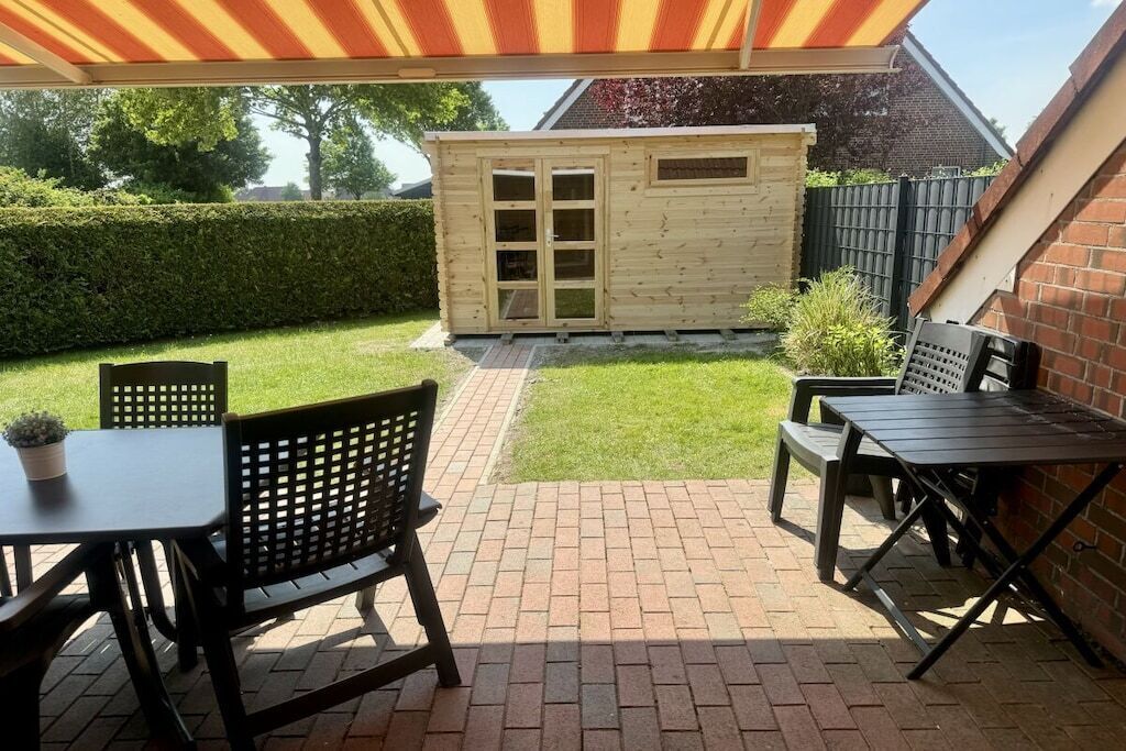 Une terrasse avec un sol en briques, une table en bois et deux chaises.