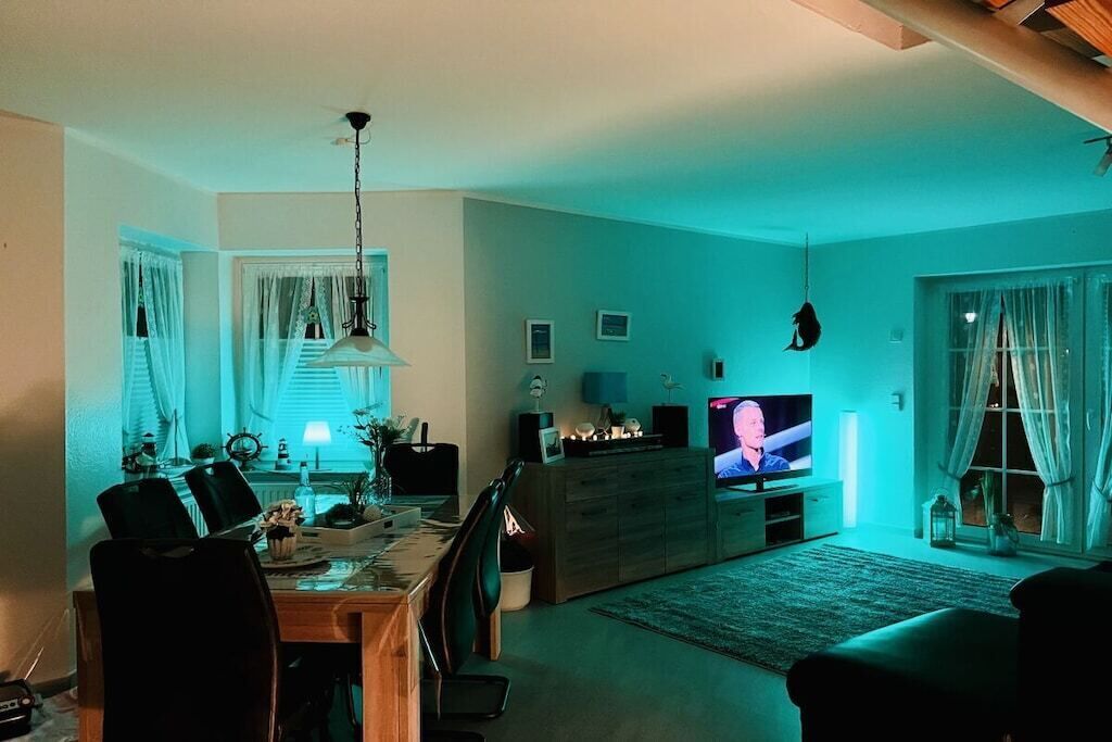 A living room with a dining area, a television, and a chandelier.