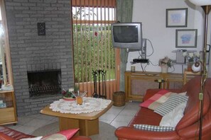 A living room with a fireplace, a television, a sofa, and a coffee table. - in the Strandslag 103 holiday park in Julianadorp (Julianadorp)