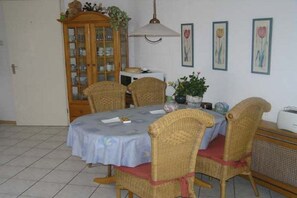 Un coin repas avec une table ronde, des chaises en osier, un buffet et des œuvres d’art murales.