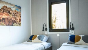 A room with two beds, a window with a view of trees, and a painting on the wall. - Colorado-inspired Cottage for 6 in Slagharen (Slagharen)
