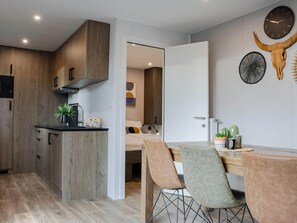 A modern kitchen with wooden cabinets, a black countertop, and a plant.