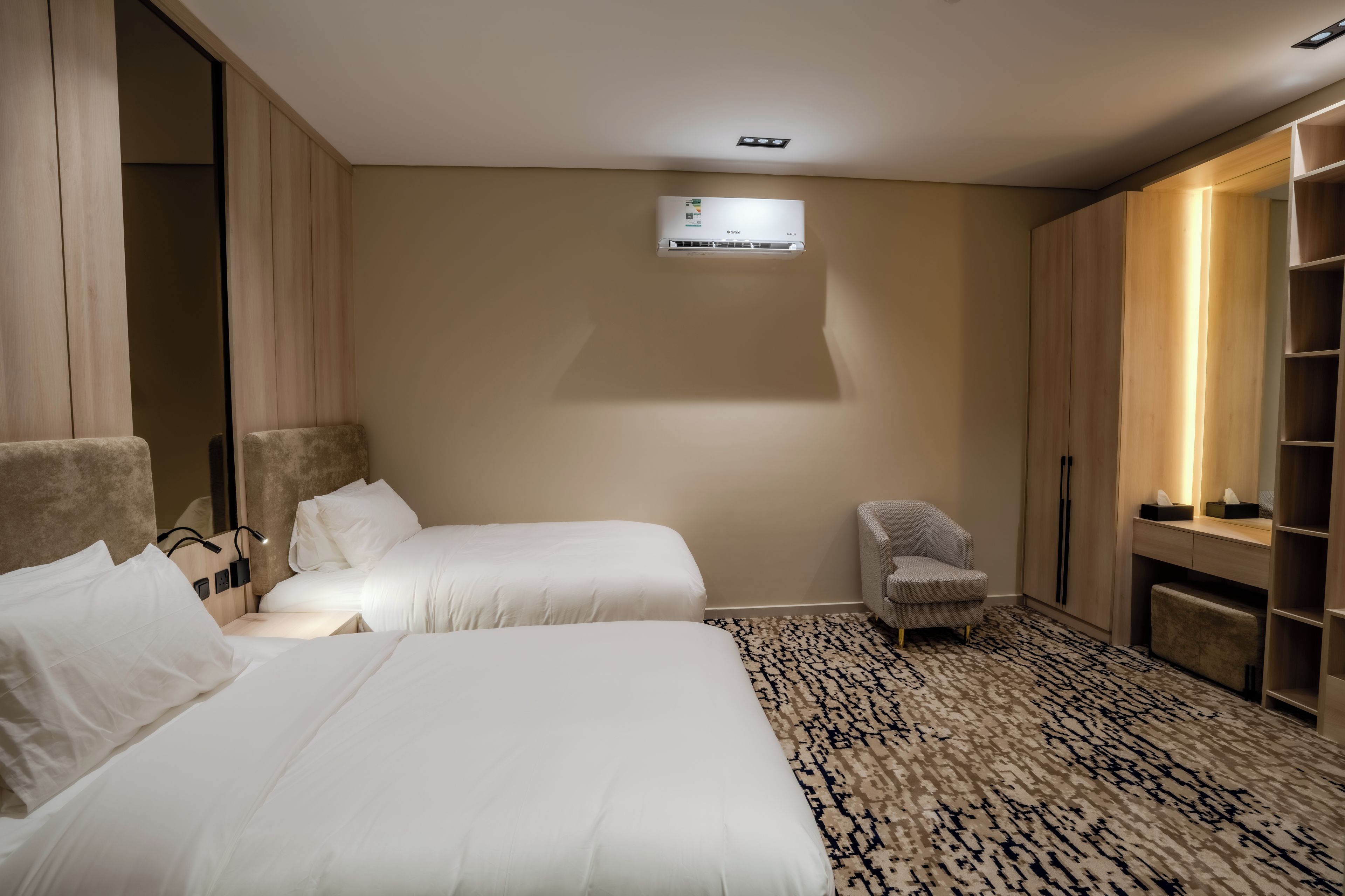 Une chambre d’hôtel avec deux lits, une chaise, une armoire et un appareil de climatisation.