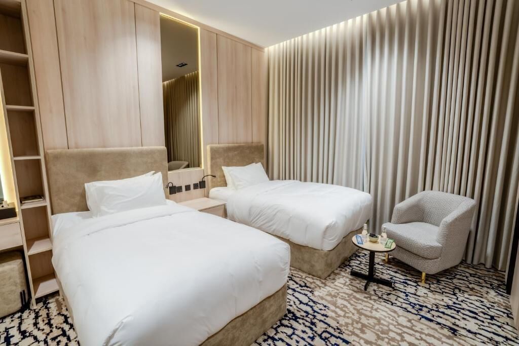 Une chambre d’hôtel avec deux lits, une petite table, une chaise et une armoire.