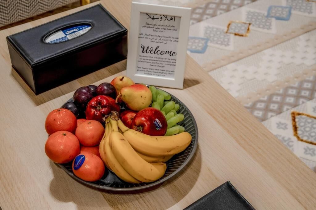 Un panneau d’accueil et une assiette de fruits, notamment des oranges, des bananes et des pommes.