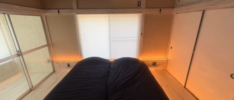 A room with a bed, a window, and an air conditioning unit.