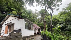 Un chalet rustique doté d’une terrasse en bois, entouré d’une forêt dense.