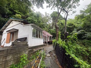 A rustic cabin with a wooden deck, surrounded by dense forest. - Surrounded by forests and rivers, this whole-house rental offers a special getaway where you can enjoy camping, barbecues, and bonfires amidst nature. (富津市萩生)