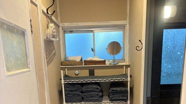 Une salle de bain équipée d’une douche, de toilettes et d’un meuble de rangement contenant des serviettes et un panier.