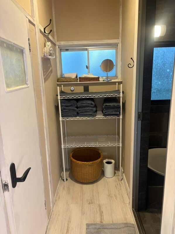 A bathroom with a shower, a toilet, and a storage unit with towels and a basket. - Surrounded by forests and rivers, this whole-house rental offers a special getaway where you can enjoy camping, barbecues, and bonfires amidst nature. (富津市萩生)