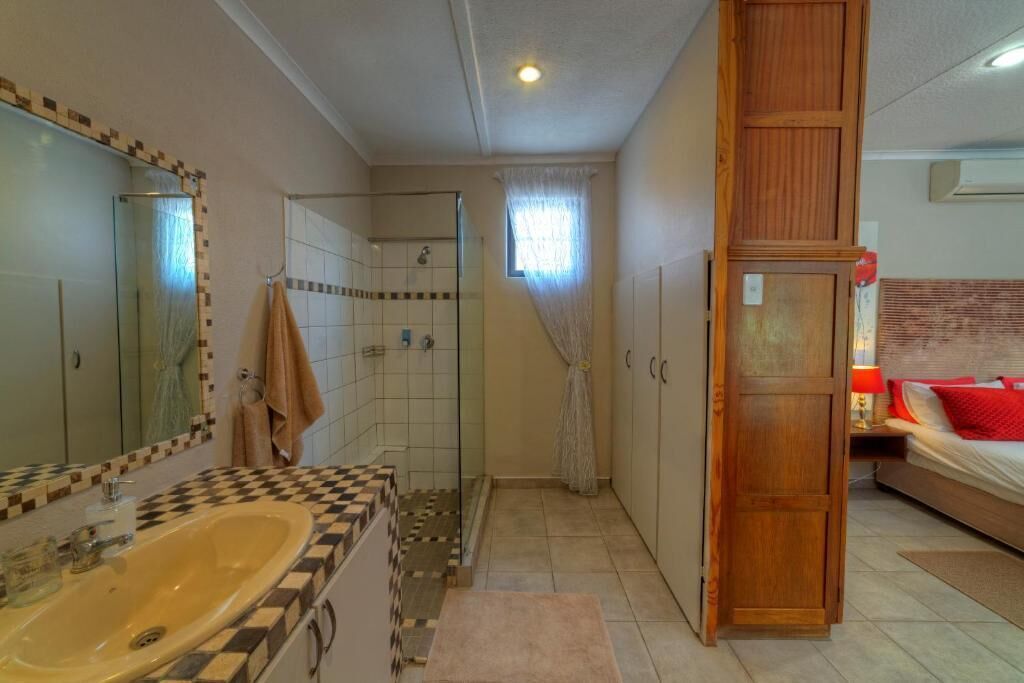 Un baño con tocador de baldosas a cuadros, cabina de ducha de vidrio y armario de madera.