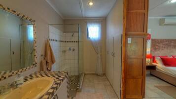 Un baño con tocador de baldosas a cuadros, cabina de ducha de vidrio y armario de madera.
