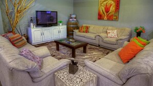 A living room with a television, sofa, coffee table, and decorative items.