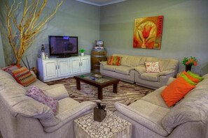 A living room with a television, sofa, coffee table, and decorative items.