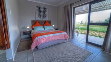 A bedroom with a bed, nightstands, a lamp, a large window, and a view of the outdoors.