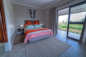 Un dormitorio con una cama, mesitas de noche, una lámpara, un ventanal y vistas al exterior.