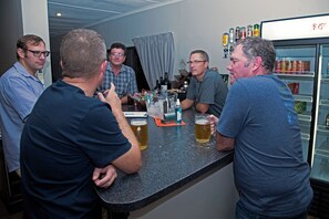 Een groep mensen in een bar, met een koelkast vol drank.