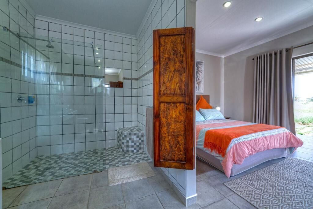 Un baño moderno con ducha, una puerta grande de madera y una cama con alfombra estampada.