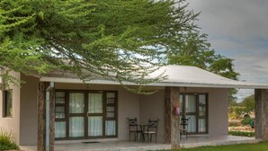 A single-story building with a covered porch, two chairs, and a small table.