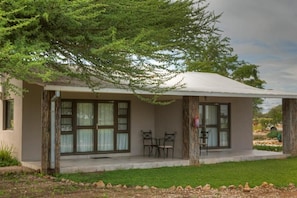 A single-story building with a covered porch, two chairs, and a small table.