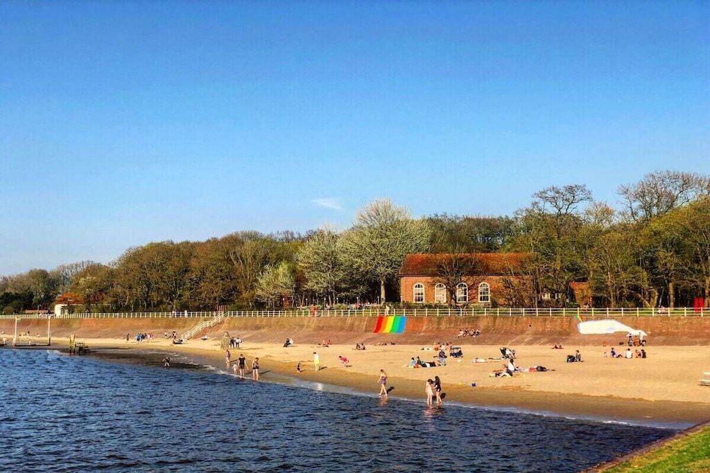 A beach with people, a building, and trees.