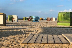 Een strand met meerdere kleurrijke strandhuisjes en een houten loofpad dat naar de zee leidt.