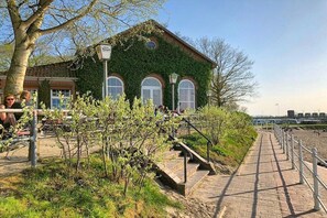 Een gebouw met een groene gevel, een bakstenen voorgevel en een verhard pad er naartoe.
