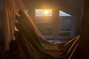 A hammock in a room with a view of the sunset through a window. - Holiday home in Süssau with swimming pool (Süssau)