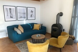A living room with a sofa, a round coffee table, a yellow armchair, a fireplace, and three framed pictures on the wall. - Holiday home in Süssau with swimming pool (Süssau)