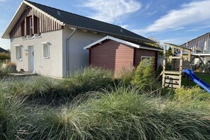 A two-story house with a red garage door, a white front door, and a small porch. - Holiday home in Süssau with swimming pool (Süssau)