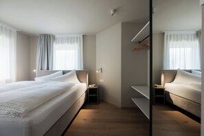 Une chambre d’hôtel moderne avec un grand lit, une table de chevet, un miroir et une armoire.