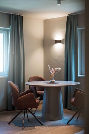 A modern dining area with a round table, four chairs, and a vase with dried flowers. - New, cozy apartment in a central location featuring Italian design and mountain views (Mühlbach)