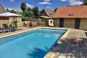 A swimming pool with a wooden deck, lounge chairs, and a small table. - The chair and the pool near Sarlat (Veyrines-de-Domme)