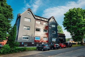 Een meerlaags woongebouw met een parkeerplaats ervoor.