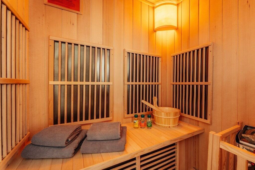 A wooden sauna with benches, a bucket, and bottles of oils.