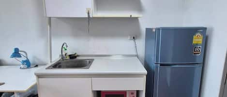 Una kitchenette compacta con un lavabo, un microondas y un refrigerador.